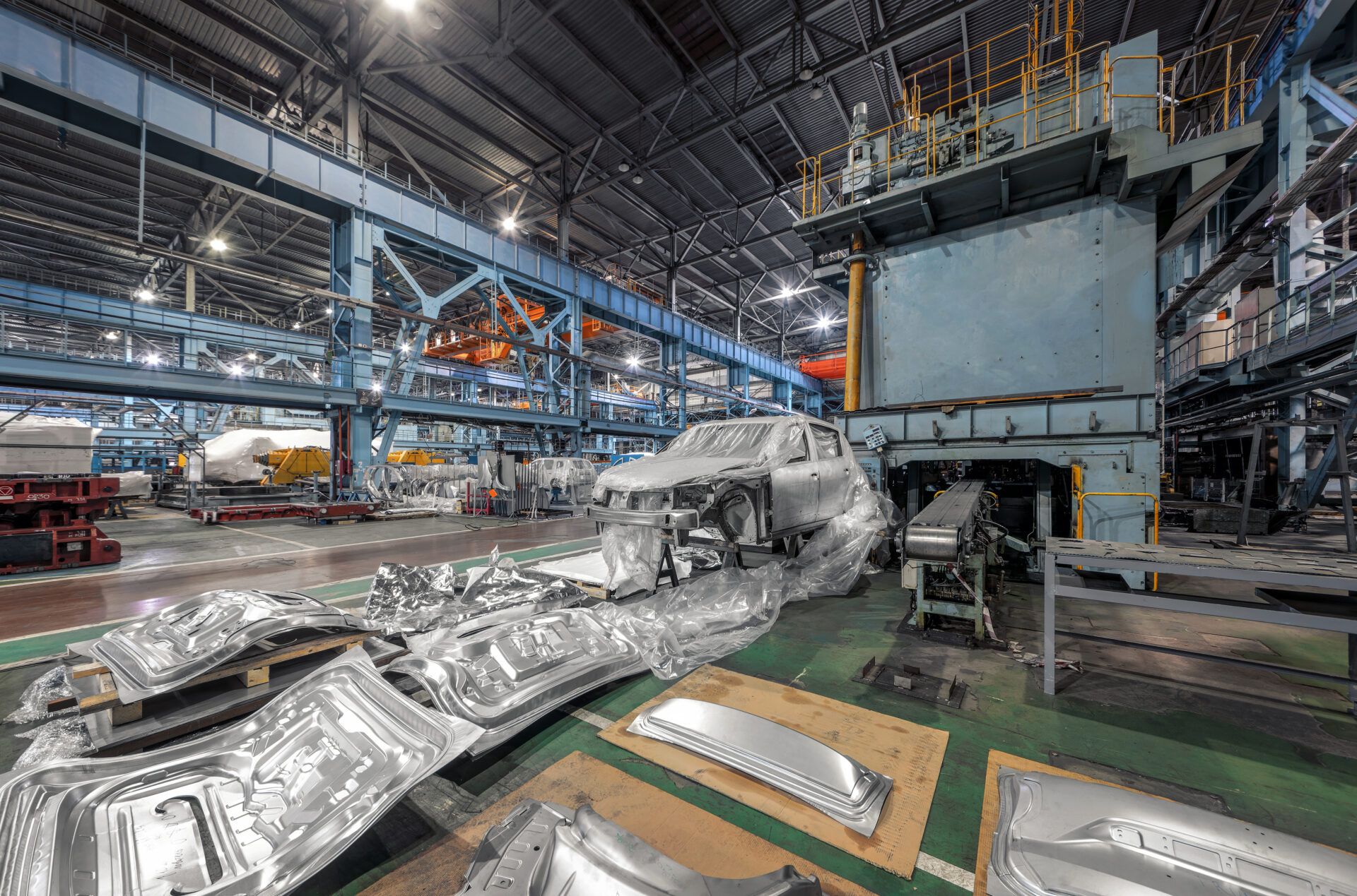 Sheets of aluminum and metal in a factory by an unfinished car